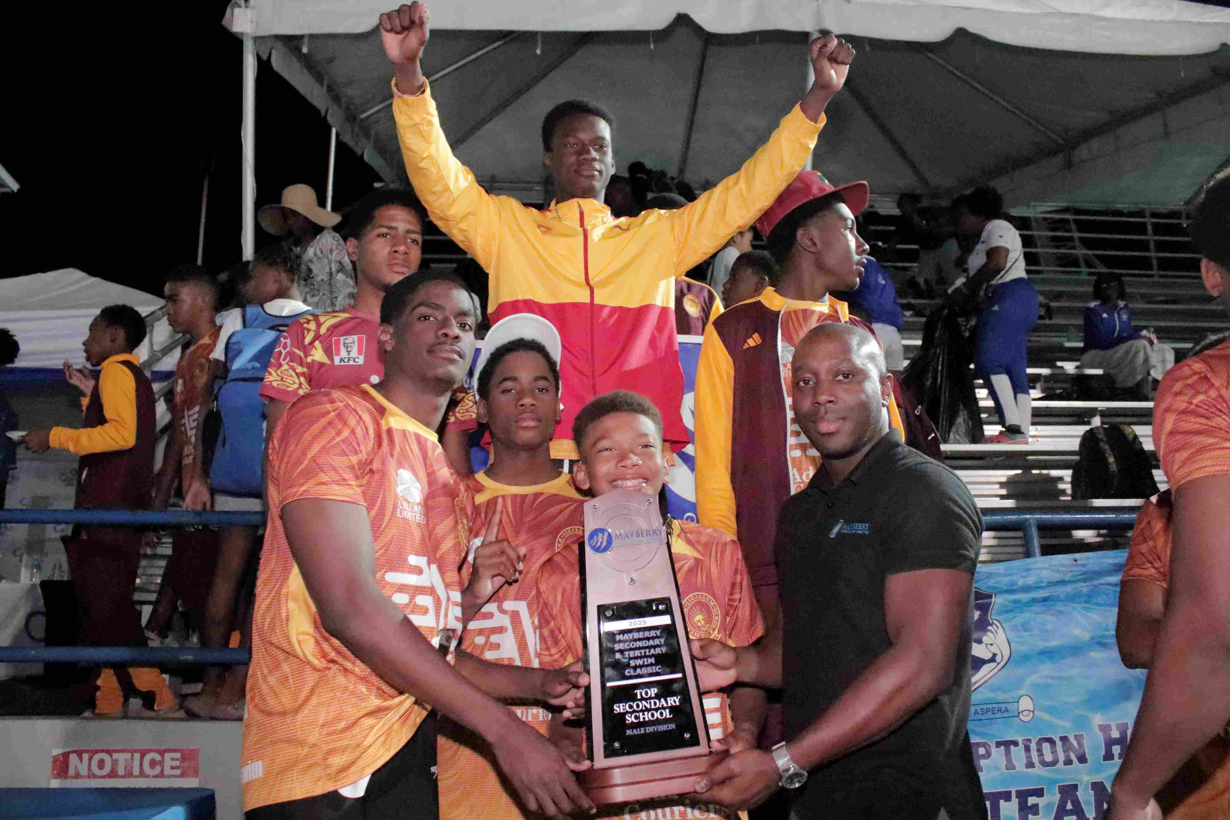Mayberry Investments Limited Assistant Vice President of Research, Jason Martinez (left), presents the winner's trophy to Wolmer’s Boys' School, the Top Performing Boys' School, following the conclusion of Day 1 of the Mayberry 2025 Swim Classic at the National Stadium on Friday Mayberry 2025 Swim Classic Delivers Thrilling Competition
