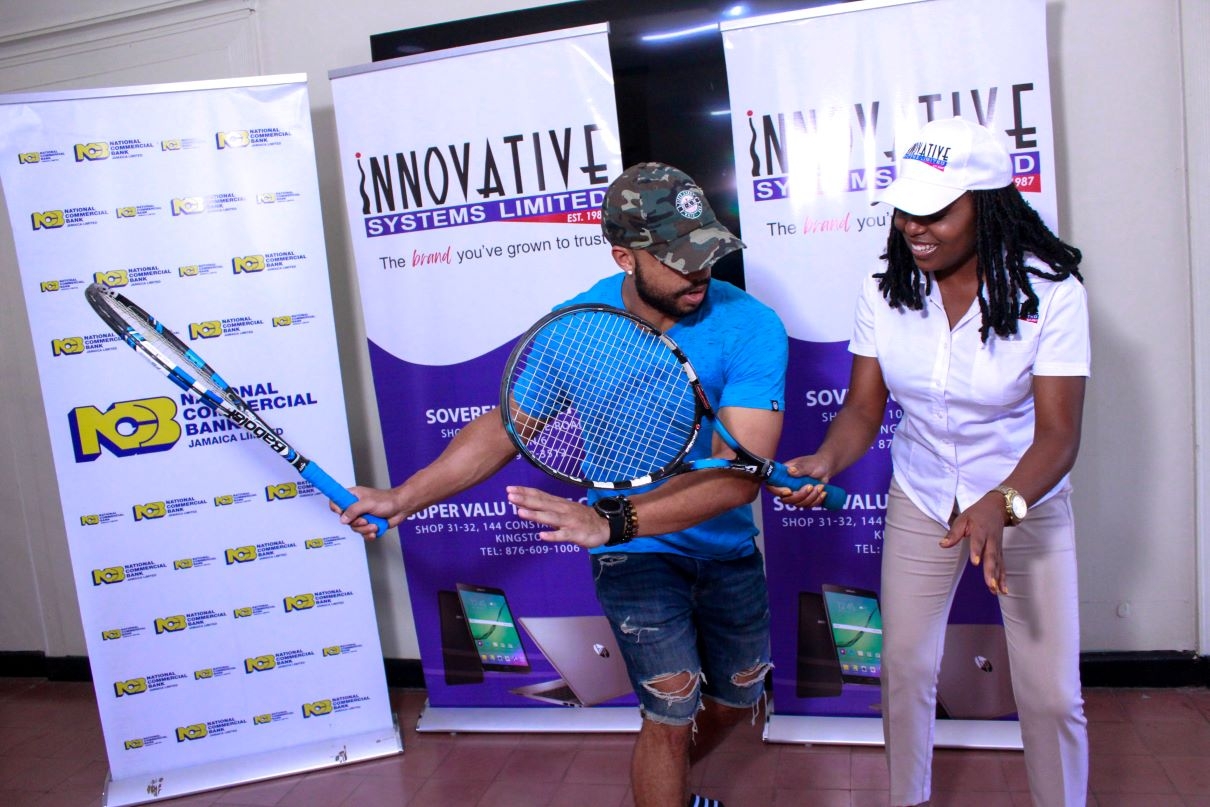 Seretse Bell (left) teaches Yanique Hall, Sales & Marketing Manager- Innovative Systems Limited, a few techniques at the launch of the 2023 Innovative Invitational Amateur Tennis Classic on Tuesday at the Liguanea Club.